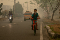 A student goes to school wearing a mask to protect him from the smoke that blankets the city of Palangka Raya, Central Kalimantan.